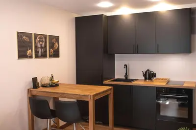 a kitchen with a wooden table and black cabinets at Euforia - Jacuzzi apartment Ukmergė in Ukmergė