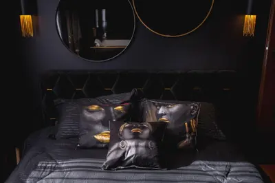 a bedroom with a bed with black pillows with a mask at Euforia - Jacuzzi apartment Ukmergė in Ukmergė