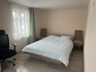 a bedroom with a bed and a chair and a window at Small house in Vilnius