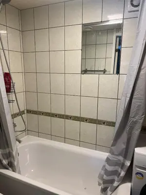 a bathroom with a bath tub and a mirror at Small house in Vilnius