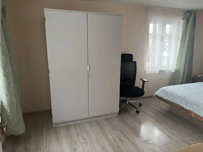 a bedroom with a white cabinet and a bed and a chair at Small house in Vilnius