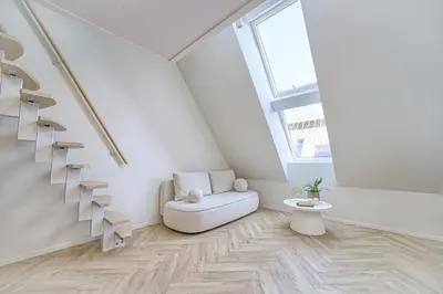 a white living room with a chair and stairs at Amazing apartments 2 x free parking x 24x7 in Vilnius