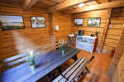 a wooden cabin with a wooden table and benches at 6 vietų namelis ant ežero kranto in Sudervė