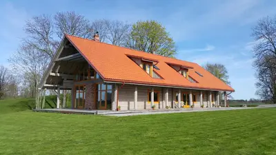 a house with an orange roof on a green field at Roksala in Taručiai