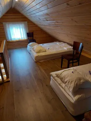 a attic room with two beds and a table and chairs at Roksala in Taručiai