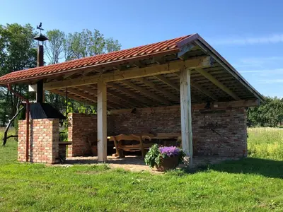 a wooden pavilion with a table in a field at Roksala in Taručiai