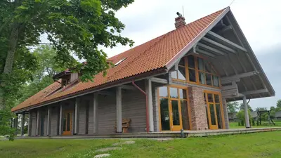 a small house with a tiled roof and windows at Roksala in Taručiai