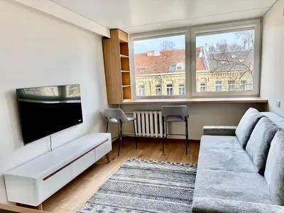 a living room with a couch and a flat screen tv at Brand new studio in the center in Vilnius