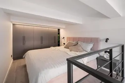 a bedroom with a large bed with gray cabinets at Pinky loft in City centre Self check-in No 3 in Vilnius