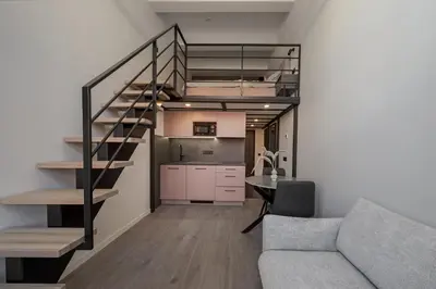 a living room and kitchen with a staircase and a couch at Pinky loft in City centre Self check-in No 3 in Vilnius