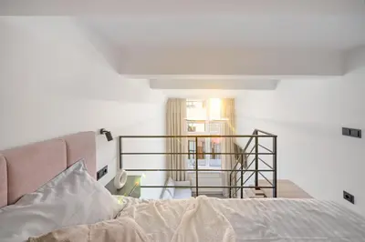 a bedroom with a bed and a stair case at Pinky loft in City centre Self check-in No 3 in Vilnius