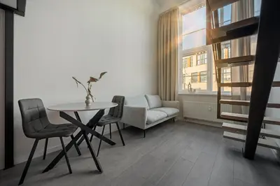 a living room with a table and chairs and a window at Pinky loft in City centre Self check-in No 3 in Vilnius