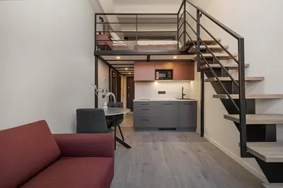 a living room with a couch and a spiral staircase at Rusty Red loft in City centre Self check-in No 2 in Vilnius
