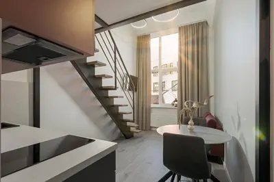 a kitchen with a table and a spiral staircase at Rusty Red loft in City centre Self check-in No 2 in Vilnius