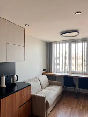 a living room with a couch and a kitchen at Žvėryno studija in Vilnius