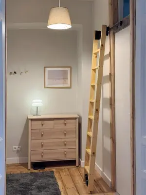 a bedroom with a ladder next to a dresser at Stepono Apartment in Vilnius