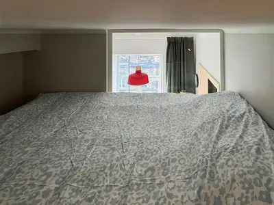 a bed in a bedroom with a window and a red lamp at Stepono Apartment in Vilnius