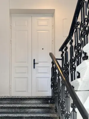 a white door with black railings next to a stairs at Stepono Apartment in Vilnius