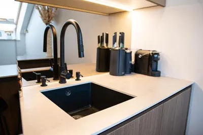 a kitchen counter with a sink and two faucets at M 8 apartment in Kaunas