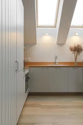 a kitchen with white cabinets and a window at Vila 44 in Druskininkai