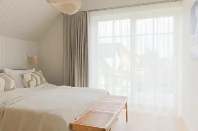 a white bedroom with a bed and a large window at Vila 44 in Druskininkai