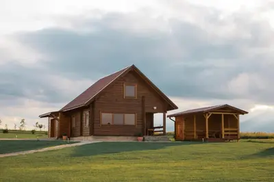 a log cabin with a porch and a gazebo at Sodyba prie Vidinksto ežero in Pakalniai