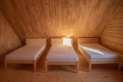 a room with two beds in a wooden cabin at Sodyba prie Vidinksto ežero in Pakalniai