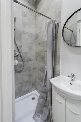 a white bathroom with a shower and a sink at Centrinis butas šalia senvagės in Panevėžys