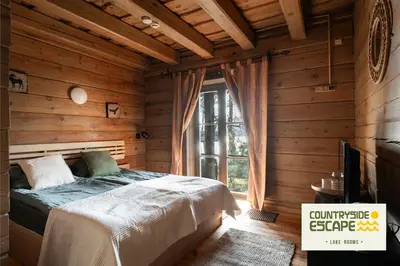 a bedroom with a bed in a room with wooden walls at Countryside Escape - Lake Rooms in Trakai