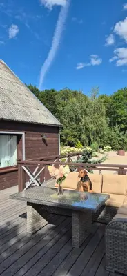 a patio with a table and a couch on a deck at Stonaičių sodybos Namelis in Kelmė