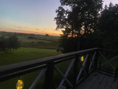 a view of a sunset from a porch with a fence at Stonaičių sodybos Namelis in Kelmė