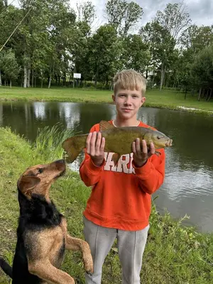 a young boy holding a fish in front of a dog at Stonaičių sodybos Namelis in Kelmė