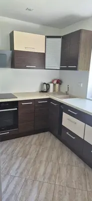 a kitchen with wooden cabinets and white counter tops at Stonaičių sodybos Namelis in Kelmė
