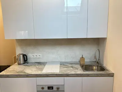 a kitchen counter with a sink and white cabinets at Feel Comfy Apartment in Druskininkai