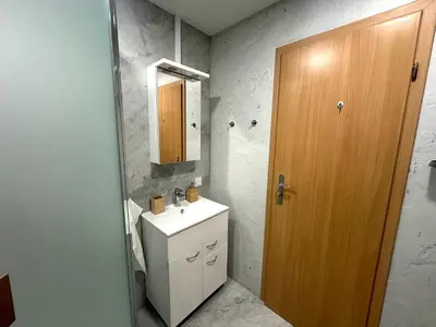 a bathroom with a white sink and a wooden door at Feel Comfy Apartment in Druskininkai