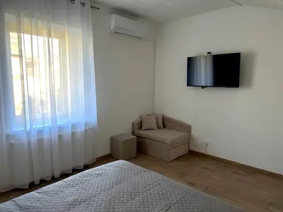 a white room with a chair and a tv on the wall at Feel Comfy Apartment in Druskininkai