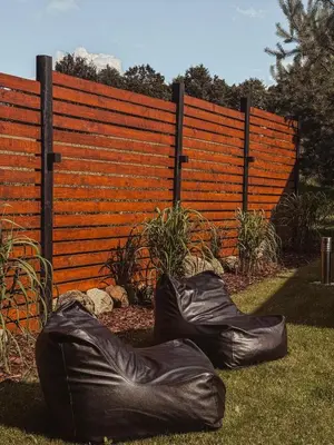 two black bags sitting on the grass in front of a fence at Bonanza Terra in Rukliai