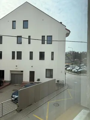 a white building with a car parked in a parking lot at Old Town Hideaway in Kaunas