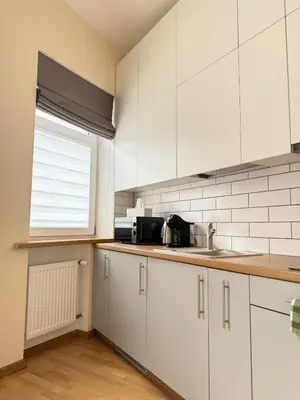a kitchen with white cabinets and a sink and a window at Old Town Hideaway in Kaunas