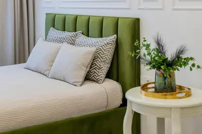 a bed with a green headboard next to a table at Frida Luxury Apartments in Šiauliai