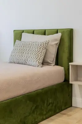 a bed with a green headboard with two pillows at Frida Luxury Apartments in Šiauliai