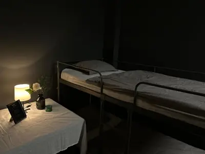 a dark room with a bed and a table with a lamp at The Kliefs Vilnius - Virtual Check-In in Vilnius