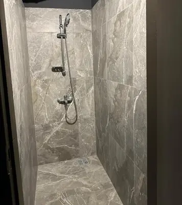 a shower in a bathroom with a stone wall at The Kliefs Vilnius - Virtual Check-In in Vilnius