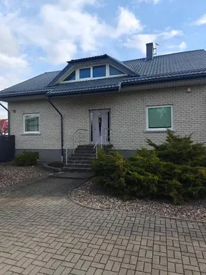 a house with a tile roof and a driveway at Vaido apartamentai in Marijampolė