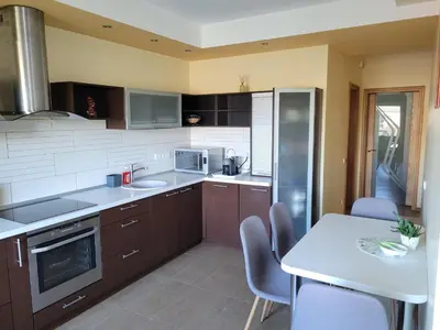 a kitchen with brown cabinets and a table with chairs at Vaido apartamentai in Marijampolė