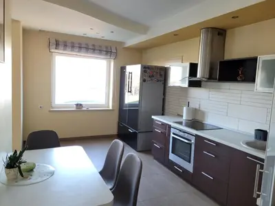 a kitchen with a table and a refrigerator and a sink at Vaido apartamentai in Marijampolė
