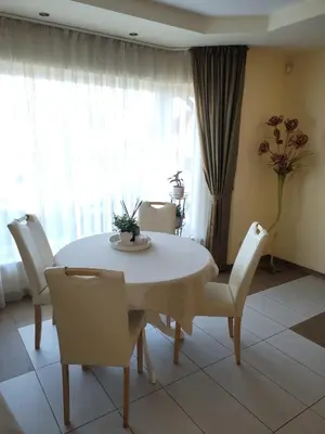 a dining room with a white table and chairs at Vaido apartamentai in Marijampolė