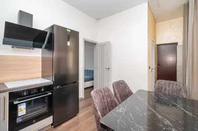 a kitchen with a refrigerator and a table with chairs at Modern flat , Self check in 24h, Netflix, parking in Vilnius