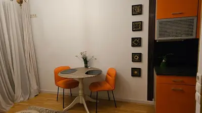 a kitchen with a table and two orange chairs at Butas su terasa Kauno centre pirmame aukšte Clinic in Kaunas