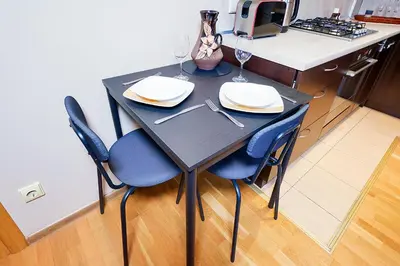 a black table and chairs in a kitchen with wine glasses at Jablonskis Apartment in Vilnius